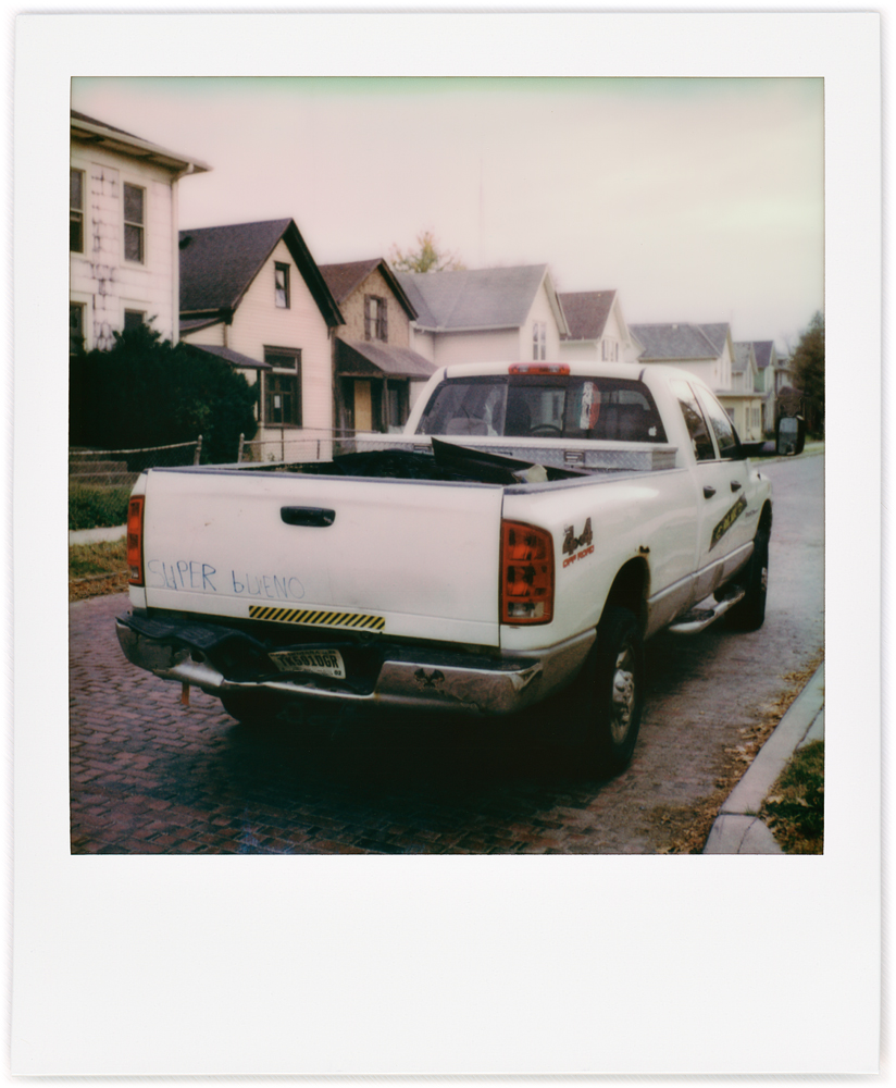 Polaroid snapshot of a white Ford F-150 pickup truck that has the Spanish phrase Super Bueno written on the tailgate in permanent marker. Parked on Fourth Street in Fort Wayne, Indiana.