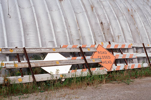 Road closed signs and barricades leaning against a Quonset hut at a county highway department garage on Yohne Road in Allen County, Indiana.