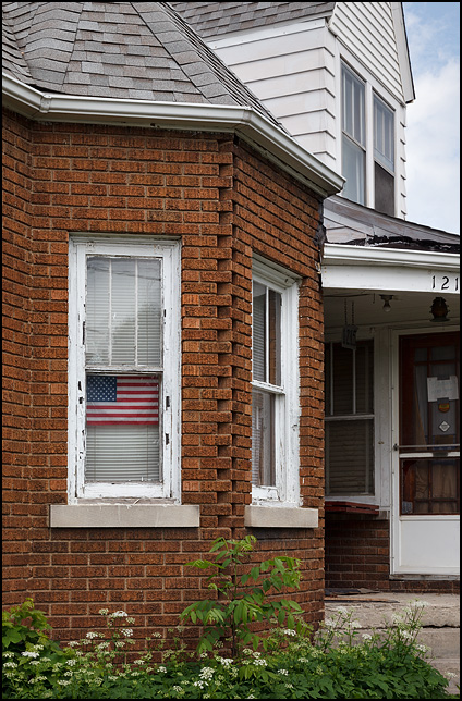 A small American flag decal in the window of an old brick house on Runnion Avenue in Fort Wayne, Indiana.