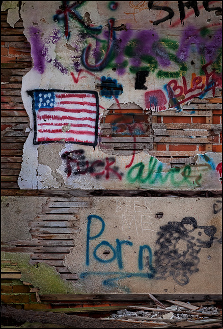 Graffiti covers the interior of an abandoned one-room schoolhouse in Indiana. It includes an American flag, the word Fuck, the word Porn, and several names of people.