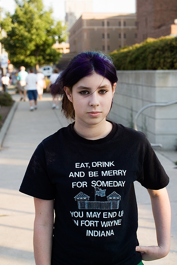 A girl at the Three Rivers Festival in Fort Wayne, Indiana wearing a t-shirt that says Eat, Drink, and be Merry, for someday you might end up in Fort Wayne, Indiana.