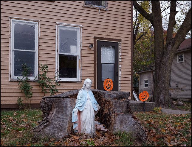 A statue of the Virgin Mary standing in a broken tree stump in front of an old house on Lavina Street in Fort Wayne, Indiana.