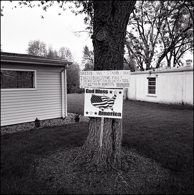A God bless America sign and an anti-government tea-party militia protest sign nailed to a tree in front of a house in the Waynedale area of Fort Wayne, Indiana.