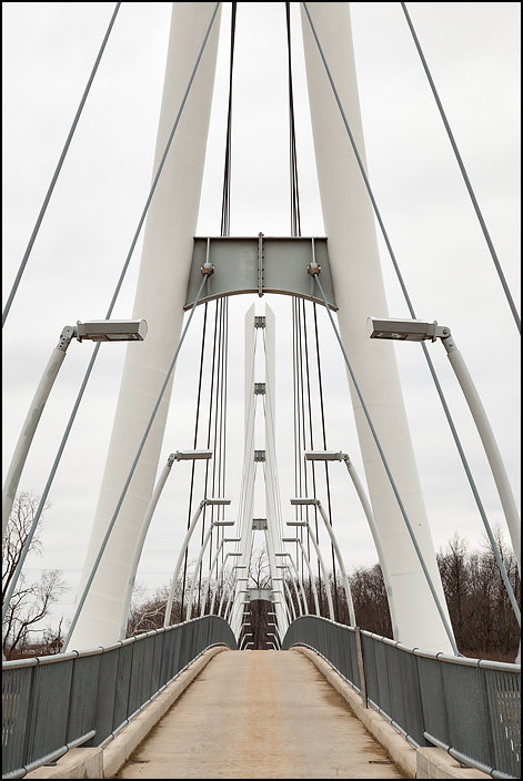 The Venderly Family Bridge is a cable-stayed footbridge over the Saint Joseph River at Indiana University Purdue University Fort Wayne. This is a view of the bridge looking west through the tall white steel towers that hold up the bridge deck.