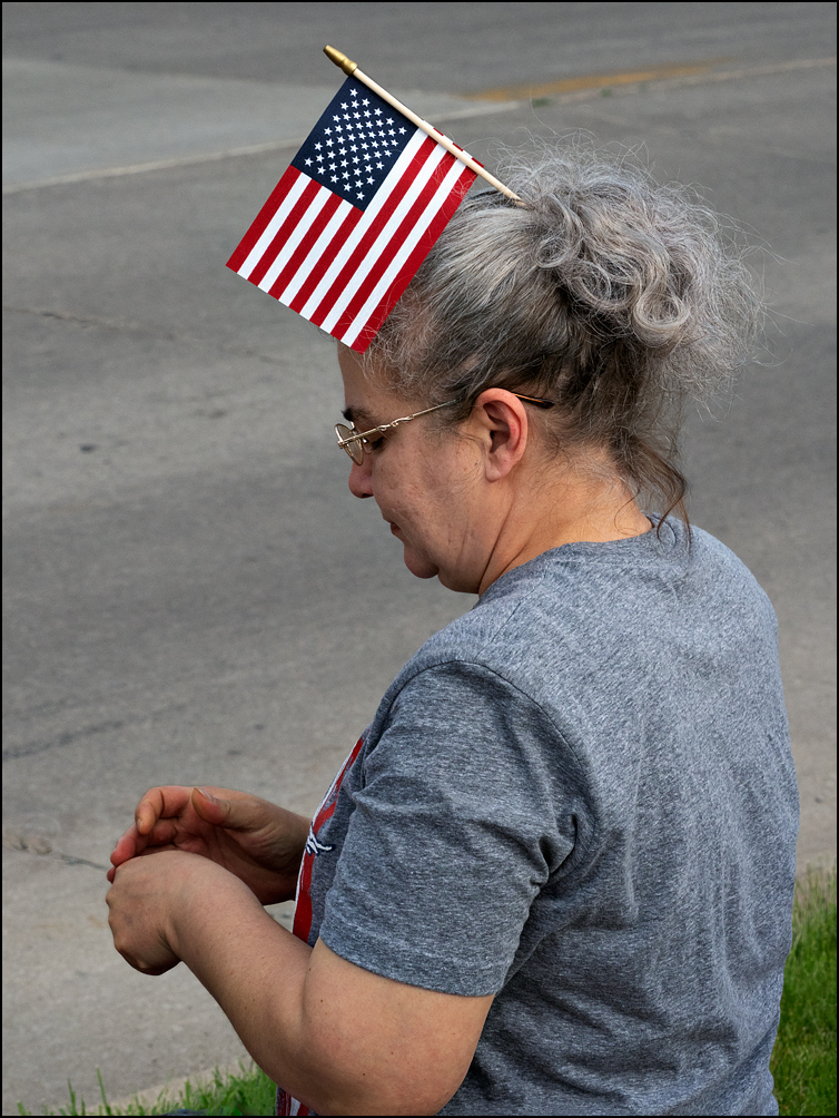 A woman with an American flag in her hair watching the 2023 Waynedale Memorial Day Parade in the Waynedale area of Fort Wayne, Indiana.