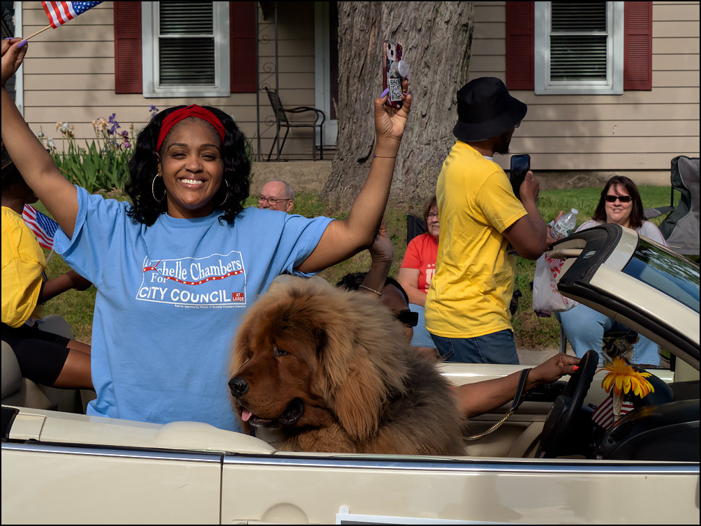 City Councilwoman Michelle Chambers, who is running for re-election, rides in the back of a convertible with a gigantic dog in the 2023 Waynedale Memorial Day Parade in the Waynedale area of Fort Wayne, Indiana.