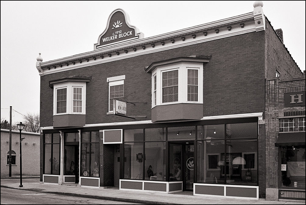 The Welker Block, a historic brick commercial building on the corner of Wells Street and Fourth Street in Fort Wayne, Indiana. The two storefronts on the first floor are The Honey Plant, and Loft House Films.