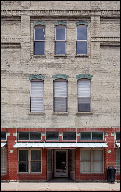 Three story brick commercial building with a vacant storefront on the main highway in the small town of Yorktown, Indiana.
